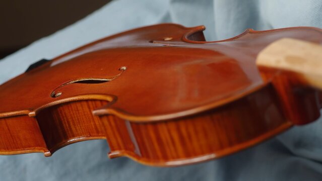 Skilled craftsman applying protective varnish to violin body, highlighting intricate woodworking techniques in musical instrument creation