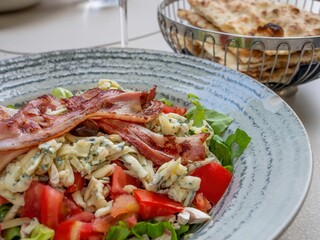 Fresh salad with bacon and blue cheese in a ceramic bowl.