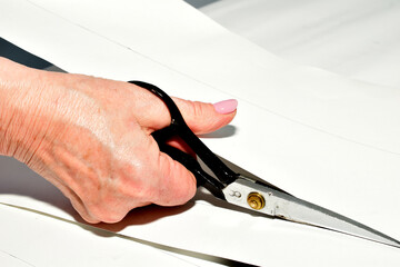 The cutter uses scissors to cut out patterns for clothing parts from paper.