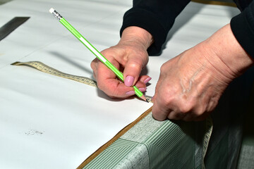 The moment when a cutter creates patterns for sewing clothes. The clothes designer applies markings...