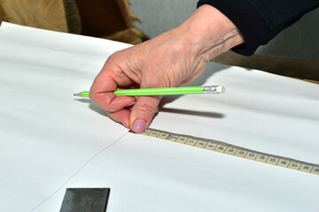The moment when a cutter creates patterns for sewing clothes. The clothes designer applies markings...