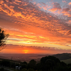 Sunset with warm orange tones casting long shadows across rolling fields and glowing golden skies