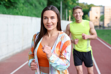 Sporty couple running at stadium, selective focus