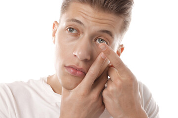 Man putting in contact lens on white background