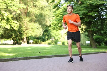 Sporty man running in park, space for text