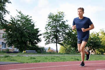 Obraz premium Sporty man running at stadium, space for text