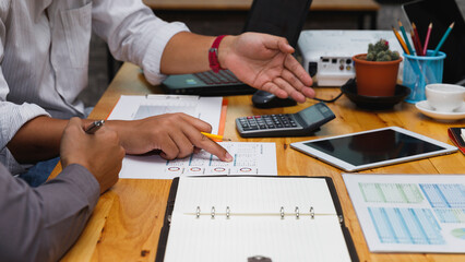Business professionals collaborate at a desk, pointing at a document during a strategic meeting. Hands in active discussion, analyzing data and pointing at a report during a business consultation.
