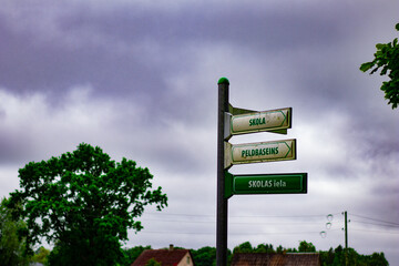 Directional street sign in Latvian language showing directions to a school, swimming pool, and...