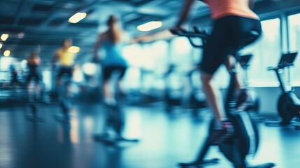A blurred background capturing a group exercise session in a well-equipped gym. Participants are engaged in activities such as HIIT, yoga, or cycling