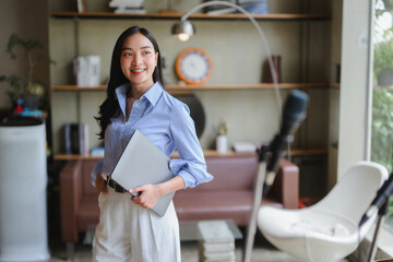 Asian businesswoman holding laptop preparing online meeting in modern office