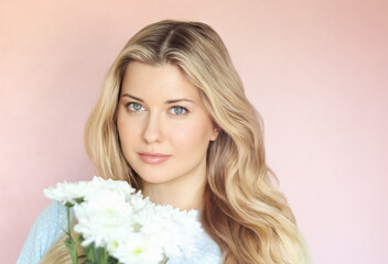 Soft floral charm with pastel pink backdrop, woman in pale blue holding white chrysanthemums in...