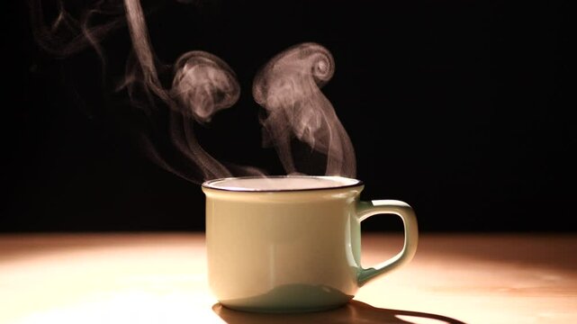 Coffee. Close-up a cup and mug of coffee on an antique table with gorgeous steam vapor spinning from the cup on an old wood table against a dark background. Concept of coffee, tea, food and beverage