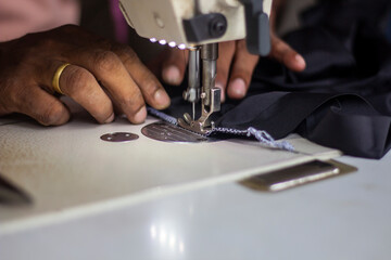 A tailor is sewing clothes with a sewing machine.