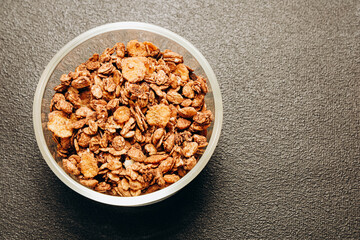 Healthy granola blend in a transparent bowl on a dark surface for nutritious breakfast ideas