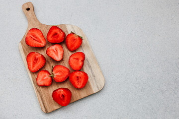 Freshly cut strawberries arranged on a wooden board ready for a summer dessert or snack
