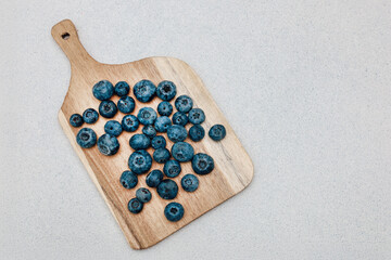 Fresh blueberries arranged on a wooden cutting board ready for cooking or snacking in the kitchen