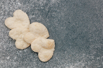 Delicate heart-shaped cookies arranged on a textured surface in a cozy kitchen setting
