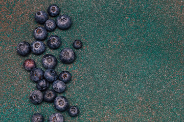 Fresh blueberries scattered on a green textured surface in natural light
