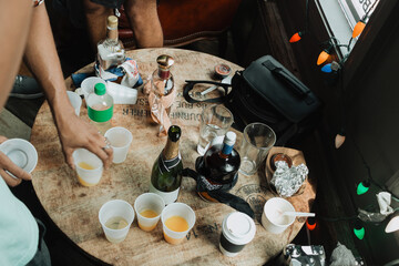 Overhead view of bottles and plastic cups with orange juice on rustic wooden table at casual indoor...