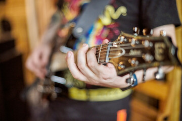 Musician hand playing an electric guitar, focusing on strings and fretboard. Captures essence of...