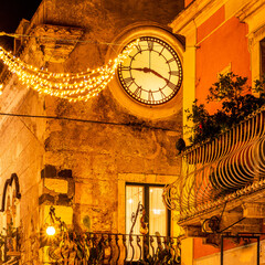 beautiful night view of vintage yellow street building with clock illuminated with holiday...