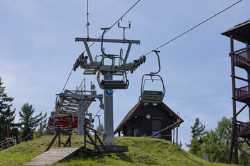 Modern ski lift cable car system with technical tower and support infrastructure on green summer...