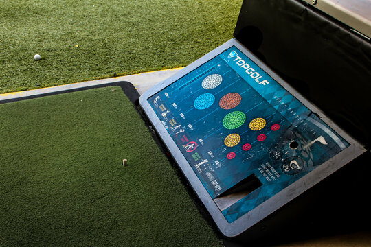 A golf practice bay at Topgolf featuring the touchscreen target system and a synthetic turf tee area. Miami, FL May 2025