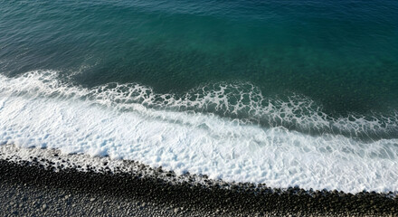 Coastal Waves Crashing on Black Pebble Beach From Above Teal Ocean