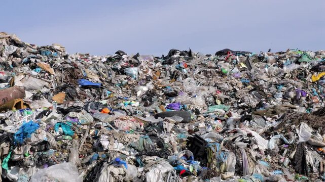 A vast landfill reveals layers of garbage and plastic debris, showcasing the environmental impact of waste accumulation over time.