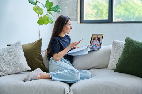 Teenage girl having online therapy sitting at home using laptop for video meeting with counselor