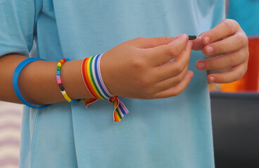 Manos de un joven con pulseras de colores del arcoíris apoyo lgtbi