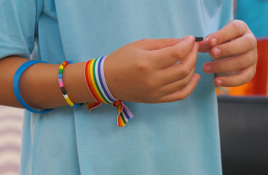 Manos de un joven con pulseras de colores del arco&iacute;ris apoyo lgtbi