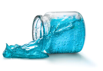 A bright blue hair styling gel spill out of a glass jar isolated on white
