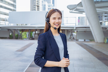Smiling asian businesswoman woman consultant wearing microphone headset of customer support phone operator at walkway in the office area