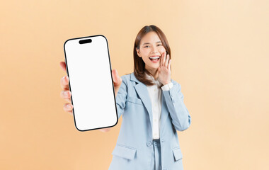 Confident Asian businesswoman holding big smartphone mockup of blank screen and smiling on beige color background.