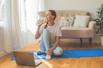 Young woman practicing yoga at home on a sunny day. Serene morning light streaming through the...