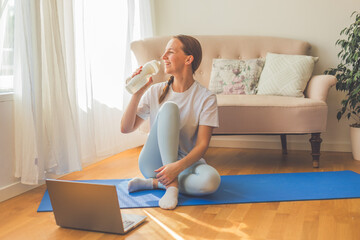 Young woman practicing yoga at home on a sunny day. Serene morning light streaming through the...