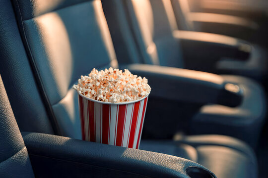 Movies and popcorn. Pop corn at cinema. Family film night concept. Action or romantic comedy entertainment on screen. Dark theater with red seats. Salty snack in bucket or box. Spectator or critic pov