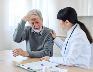 Portrait of a female doctor and senior man patient with a headache at her doctor's office in clinic