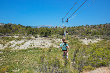 Girl child using zip line at Rhodescape Park at the artificial lake of Apolakkia in Rhodes, Greece.