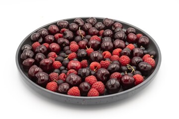 Cherry, raspberry and currant composition on a black plate on a white background - close-up of a...