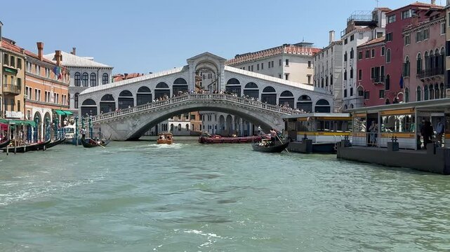 Gondolas navigating the grand canal under iconic rialto bridge on a sunny day