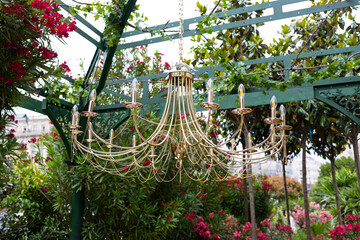 A decorative arch decorated with lush greenery and round illuminated chandeliers.