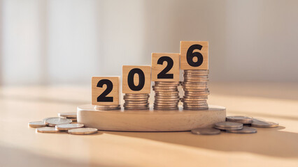 Wooden blocks with numbers 2026 stacked on coins representing financial growth and success in the new year
