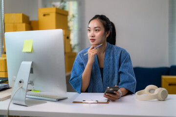 Young entrepreneur planning new marketing strategy using computer and smartphone in her home office
