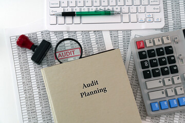 A photo illustration for Audit Planning; A detailed report is placed under a magnifying glass, symbolizing scrutiny, with a book of audit planning displayed in the foreground