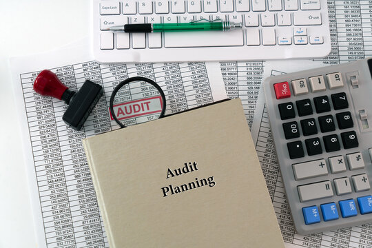 A photo illustration for Audit Planning; A detailed report is placed under a magnifying glass, symbolizing scrutiny, with a book of audit planning displayed in the foreground