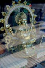 Golden ganesha statue sitting in ornate frame behind glass
