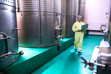 Expertise modern male wine cellar  maker holding laptop checking quality control and creating test...