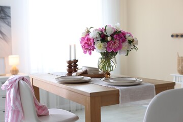 Beautiful table setting with bouquet of peonies in dining room. Interior design